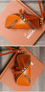 Detail of vintage orange vegetable tanned leather key pouch with double zippers and wrist strap