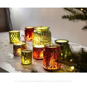 Détail de photophores de Noël en verre avec motifs de rennes et sapins posés sur la neige