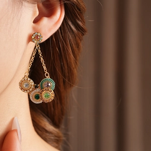 Gros plan de boucles d'oreilles vintage dorées avec pierres rondes sur un mannequin