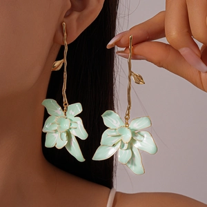Elegant mint green flower drop earrings with golden branch hooks on a female model