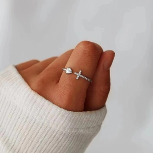 Detailed view of adjustable silver ring with heart and sparkling cross on finger