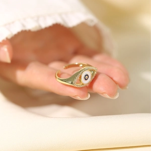 Golden Evil Eye open ring with blue and white accents worn on a model's finger
