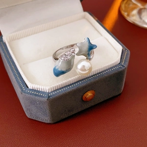 Detail view of silver open ring with blue starfish enamel and a white pearl on velvet box