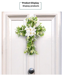 Detail of cross-shaped lily wreath decoration hanging on a white door for Easter