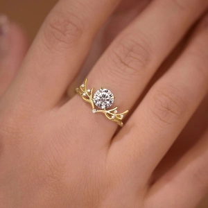 Elegante anello a corna dorate con un grande zircone rotondo e piccoli diamanti brillanti