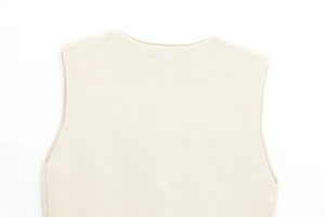 Gros plan du gilet en maille beige montrant le col rond texturé et l'épaule