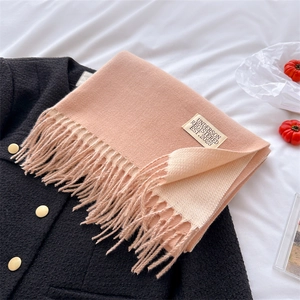 Detail of pink and beige cashmere-feel scarf with fringe and label on tweed coat