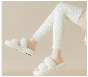 Close-up of soft white coral fleece over-knee socks paired with plush slippers