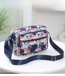 Detail shot of multi-compartment crossbody bag showing floral print and front zipper pocket