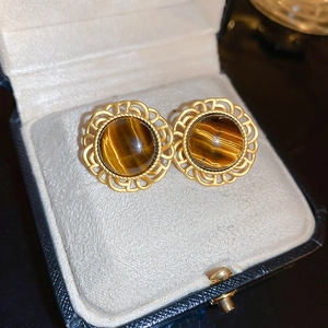 Detailed view of vintage gold stud earrings with tiger eye stone in a jewelry box