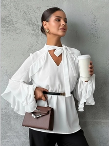 Detail of white chiffon blouse featuring ruffled bell sleeves and delicate neck tie design