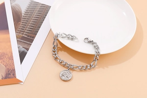 Detail of silver tree of life coin pendant on a textured stainless steel chain bracelet