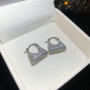 Macro shot of silver handbag-shaped earrings with square zircons in a jewelry box