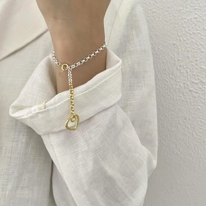 Detail of S925 sterling silver heart bracelet with two-tone gold and silver chain