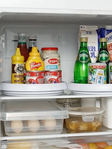 Close-up of a white rotating spice rack and egg storage box inside an organized fridge