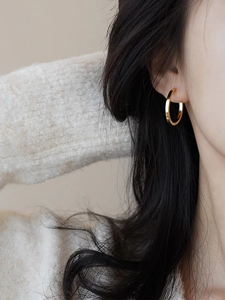 Close-up of minimalist gold hoop earrings worn by a model with a soft lighting effect