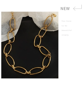 Detail view of a vintage gold-plated geometric link chain necklace on a black display tray