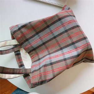Detailansicht der Vintage-Stofftasche mit Karomuster in Rot und Schwarz auf weißem Tisch.