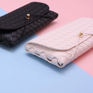 Close-up of woven texture leather glasses cases in black and pink with metal ball closure