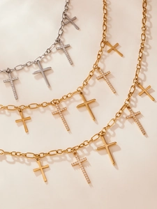 Gros plan détaillé de pendentifs croix en or et argent avec zircons 5A sur chaînes trombones