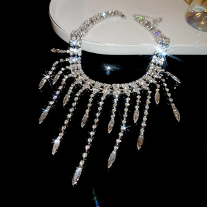 Macro shot of silver tassel necklace with rhinestones on a black reflective surface