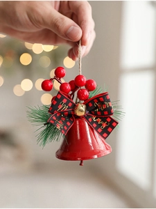 Detail of red Christmas bell ornament with plaid bow and festive pine needle decor