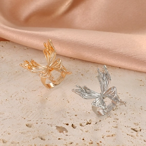 Detail of hollow butterfly rings in gold and silver finish on silk background