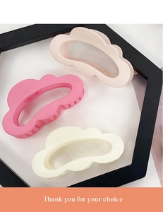 Close-up of cloud-shaped matte hair claws in pink and beige on a display stand