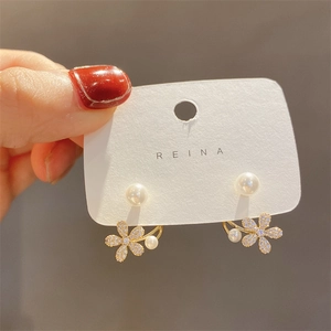 Close-up of pearl flower earrings with micro-inlaid diamonds and gold-tone finish