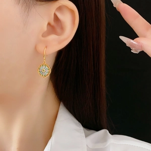 Close-up of vintage gold-plated floral enamel earrings worn by a model in a studio shot