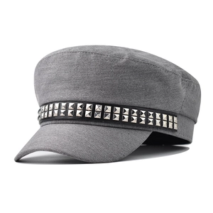 Detail of grey cadet cap featuring silver square rivets on a black decorative band