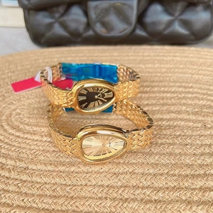 Detail of two luxury snake-head watches with metal straps on a textured straw mat