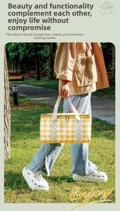 Detail of yellow checkered insulated picnic bag with grey handles on outdoor grass