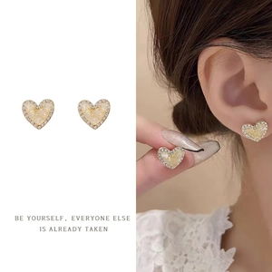 Macro detail of a heart-shaped pearl earring with rhinestone borders and gold trim