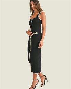 Detail of black knit dress featuring white contrast piping and decorative buttons