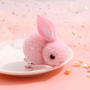 Detailed view of pink plush bunny hair clip on decorative tray with star patterns