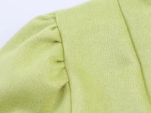 Detailaufnahme der plissierten Puffärmel-Schulter an einem hellgrünen Wildlederkleid