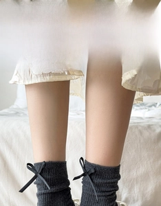 Close-up of dark grey ribbed crew socks featuring elegant black satin bow accents