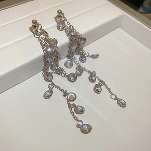 Macro view of long silver tassel earrings with multiple chains and sparkling zircons