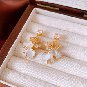 Detail of leaf earrings with gold edges, white enamel petals and sparkling zircon stud