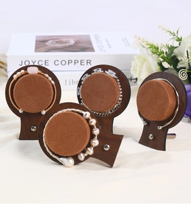 Detail of walnut wood jewelry display stand with brown velvet base and pearl bracelets