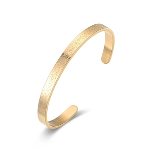 Detalle de un brazalete abierto en forma de C de acero de titanio dorado mate
