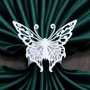 Close-up of white laser-cut butterfly napkin ring on elegant dark green fabric