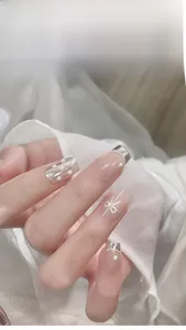Macro view of white half round pearls and bow design on pink French tip nails