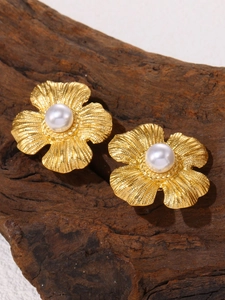 Macro detail of gold flower earrings with brushed metal petals and white pearls