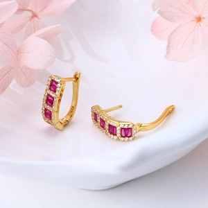 Close-up of S925 sterling silver huggie earrings with red zircon in white porcelain
