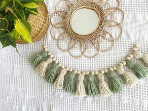 Detail of bohemian tassel banner with wooden beads and woven rattan flower mirror
