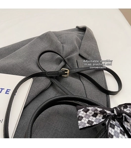 Detail of adjustable strap and metal buckle on black lychee grain leather bucket bag