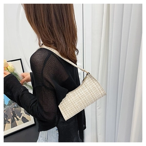 Détail du sac sous le bras en tweed beige montrant la texture tissée et le métal