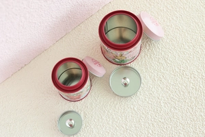 Detail of bunny tin boxes with double lids and festive floral patterns for tea storage